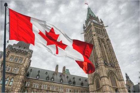 A photo of the Canadian House of Commons with a Canadian flag flying in front.