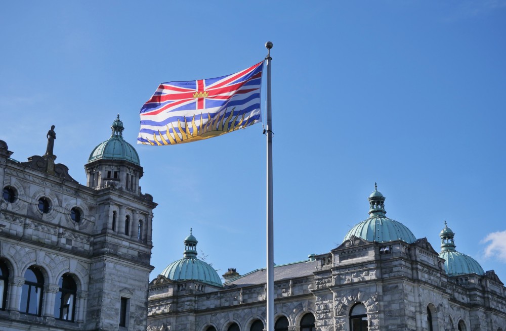 British Columbia flag and provincial legislature
