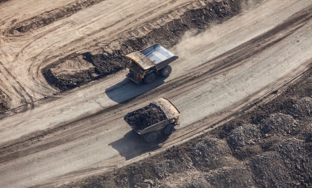 Aerial photo of large dump trucks on an oilsands mine road near Fort McMurray, Alberta.