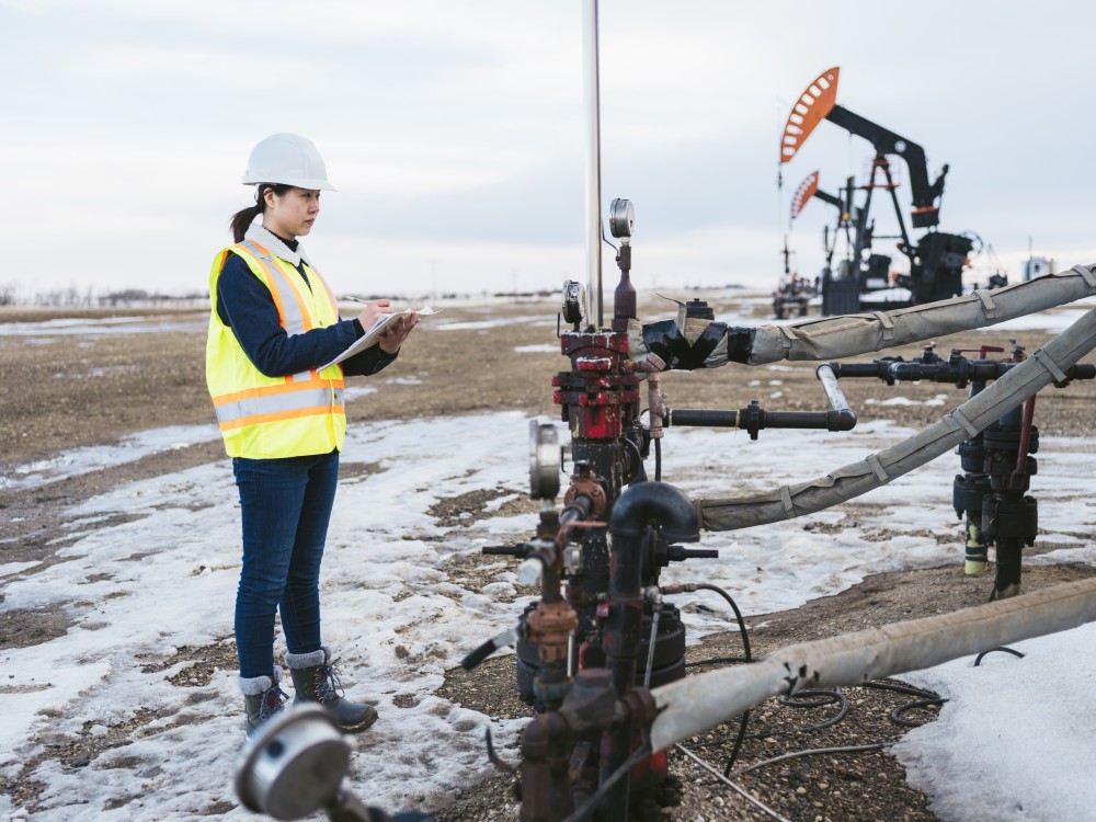 Worker inspecting oil and gas equipment in Saskatchewan, Canada.