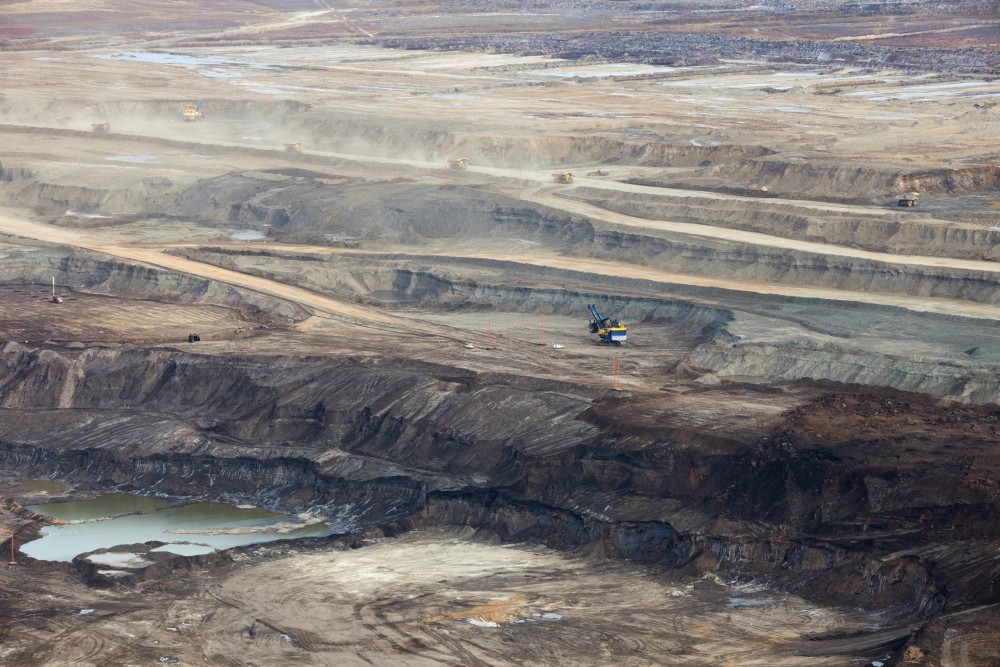 Large excavators and dump trucks mining the Alberta Oilsands.