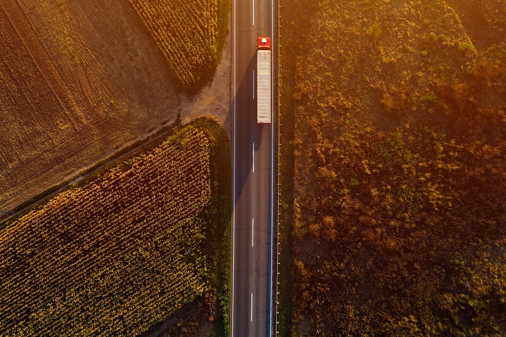 A freight truck driving along highway in farmland