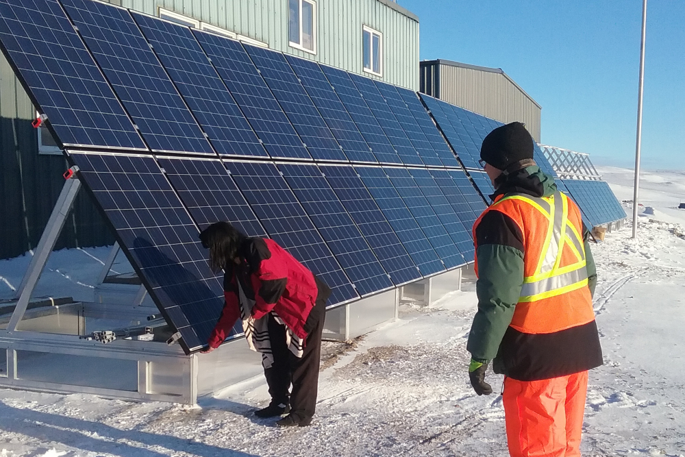 Ground-mounted solar installation in Arctic with two people