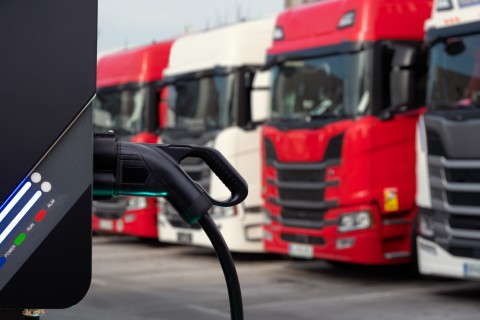 electric trucks lined up at a charging station