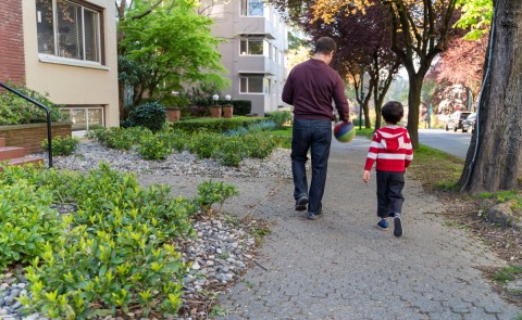 Father and son walking on a street next to MURBs