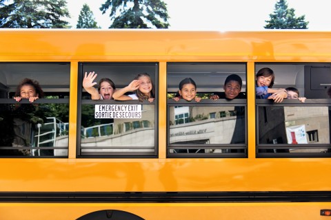 School kids hanging out of bus windows