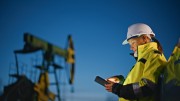 A worker at an oil and gas site recording information on an electronic device