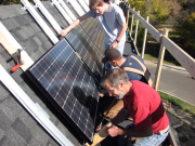 workers installing solar panels on house roof