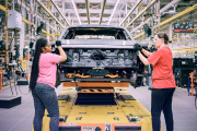 Two women working on an electric Ford F-150 Lightning pickup truck at an assembly plant